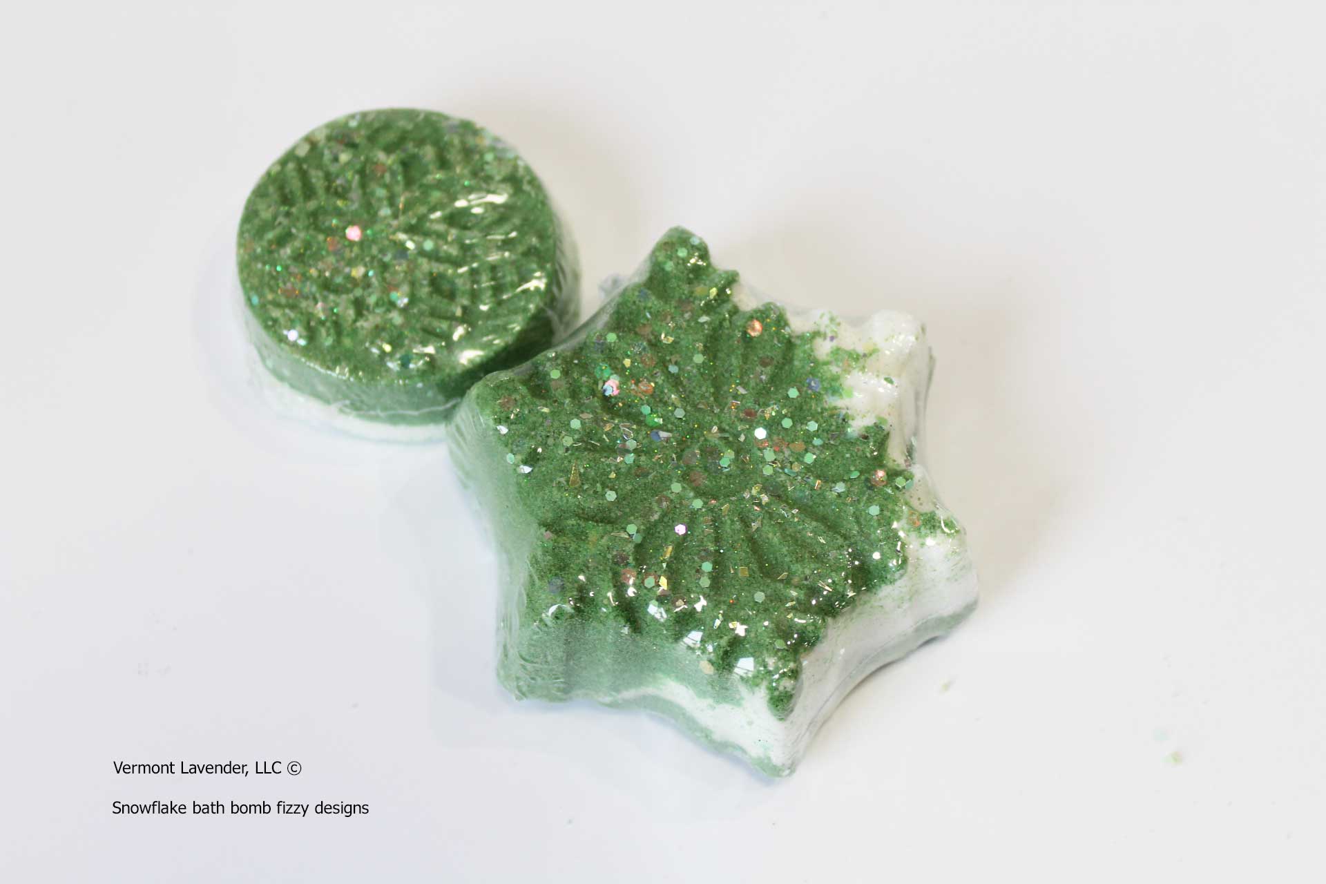 Green glittery bath bomb with snowflake design on a white background by Vermont Lavender