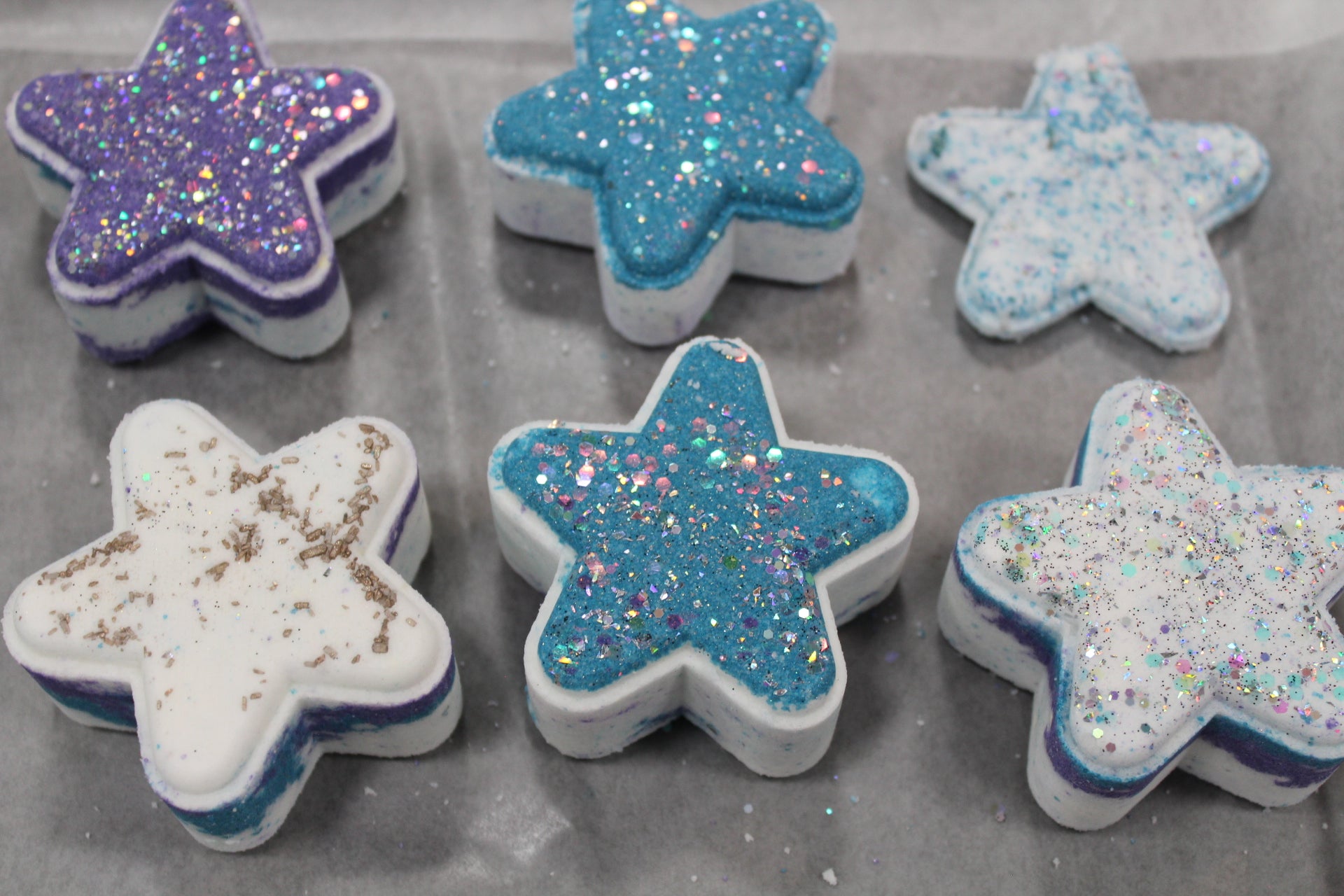 Star-shaped bath bombs with glittery and colored coatings on a gray surface Moon child fragrance oil 