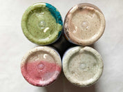 Four containers with colorful lids on a white surface
